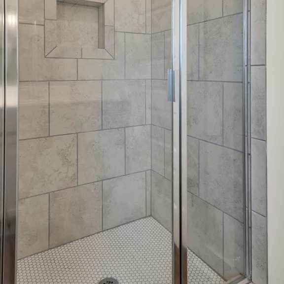 Thumbnail 7 of 9 A shower with a glass door and a tiled wall at Turnberry Park Luxury Rental Homes