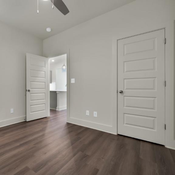 Thumbnail 5 of 9 A room with white walls and wooden floors with a ceiling fan at Turnberry Park Luxury Rental Homes.