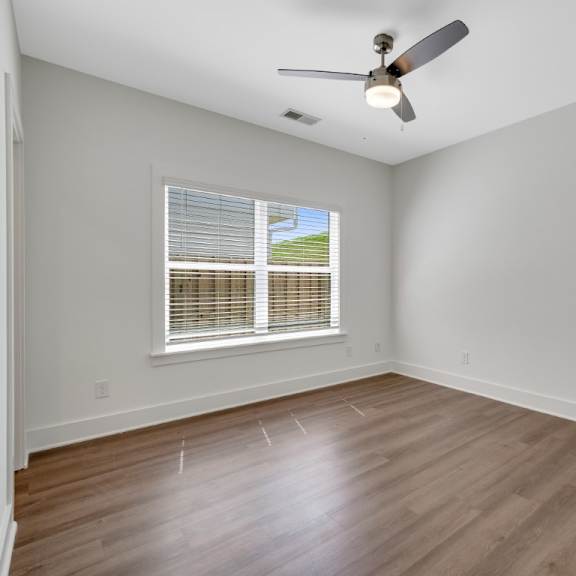 Thumbnail 8 of 13 A bedroom with a ceiling fan and a window with blinds at Turnberry Park Luxury Rental Homes