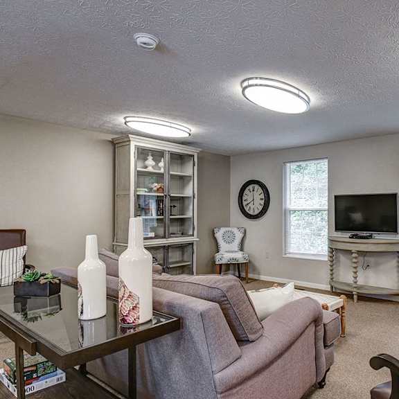 a living room with a couch, chair, and a table with two vases on it.