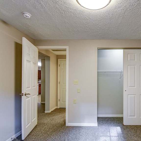 a hallway with a white door on the right and a brown door on the left.