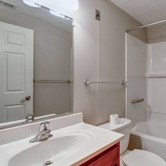 a white bathroom with a sink, toilet, and bathtub.