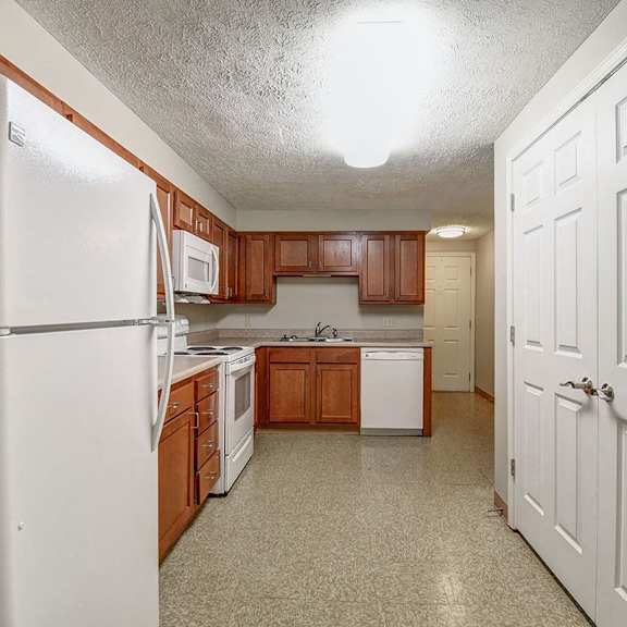a kitchen with a white refrigerator and brown cabinets.