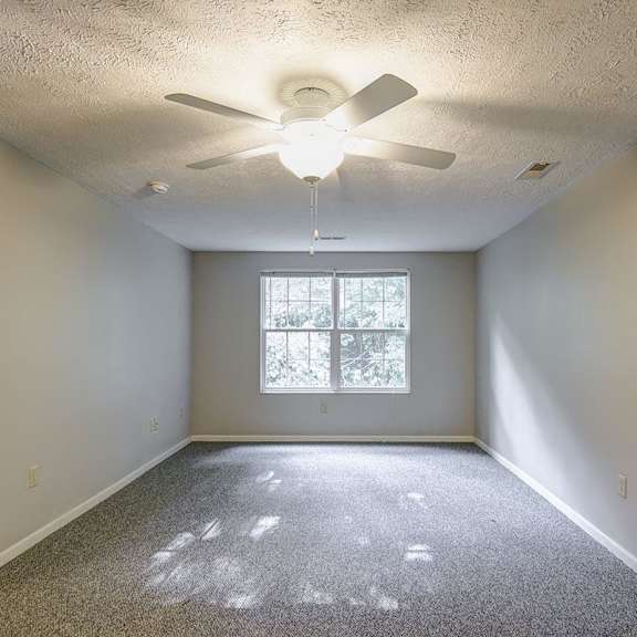 a room with a ceiling fan and a window.