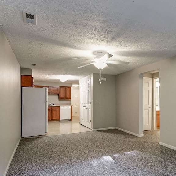 a spacious room with a refrigerator and a ceiling fan.