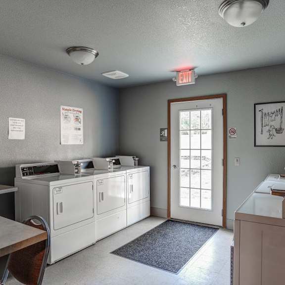 a laundry room with two washers and two dryers