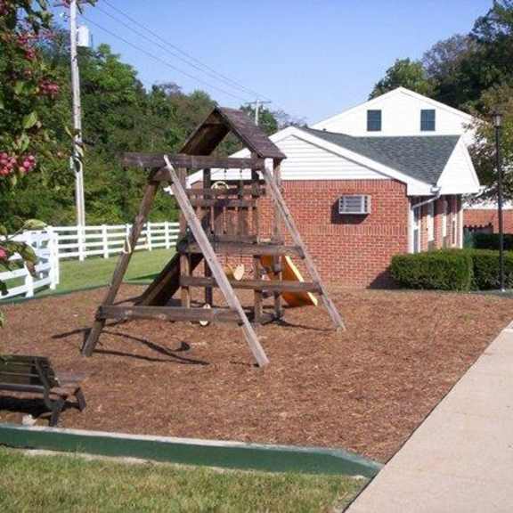 a wooden swing set in a yard in front of a house