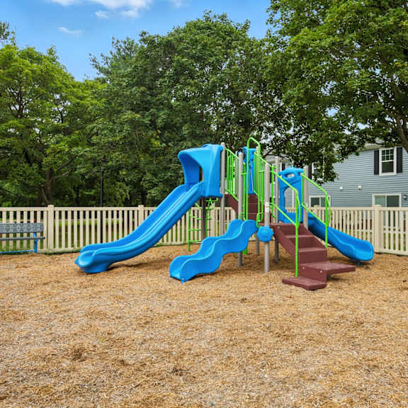 a playground with a blue slide and a brown surface.