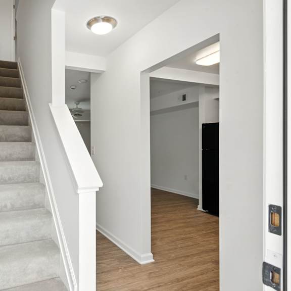 a hallway with a staircase and a door on the right.