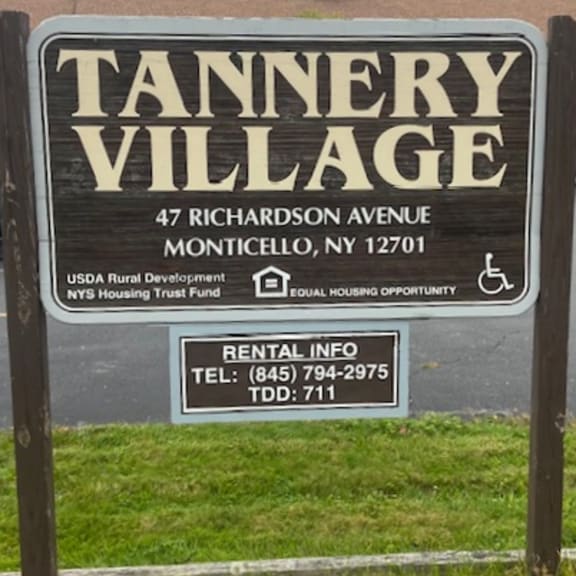 a sign for tannery village with a phone number and address.