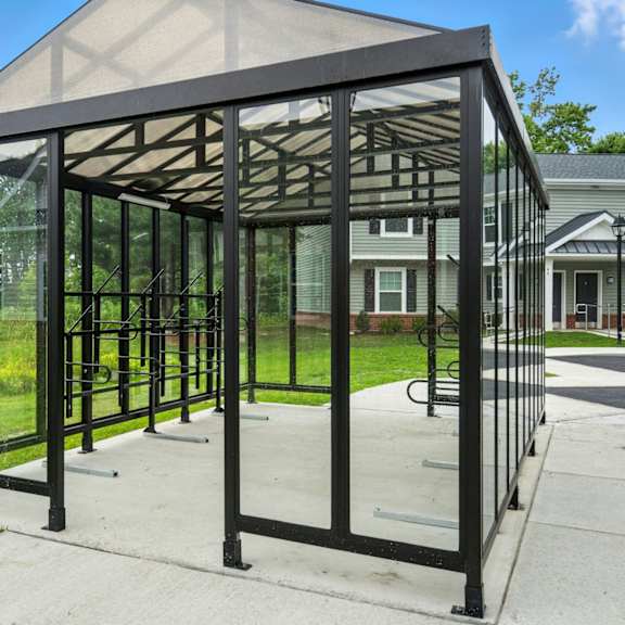 a black metal structure with glass panels is in the foreground with a house in the background.