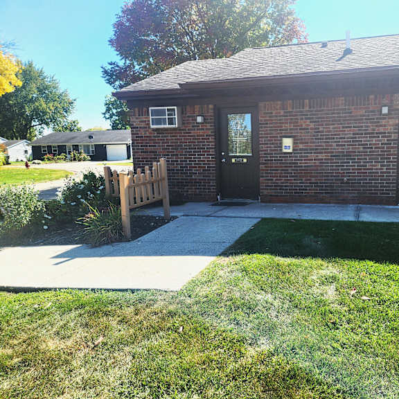 a small brick building with a porch and a wooden gate