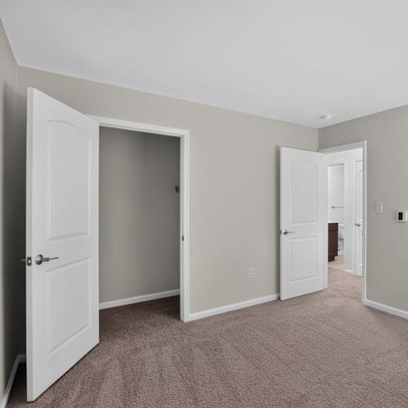 a room with carpeted floors and white walls with three doors.