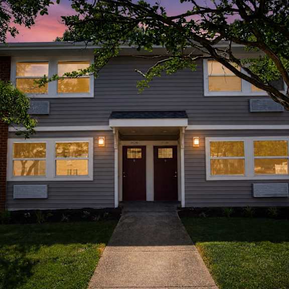 a house with a red door and windows is shown at dusk.