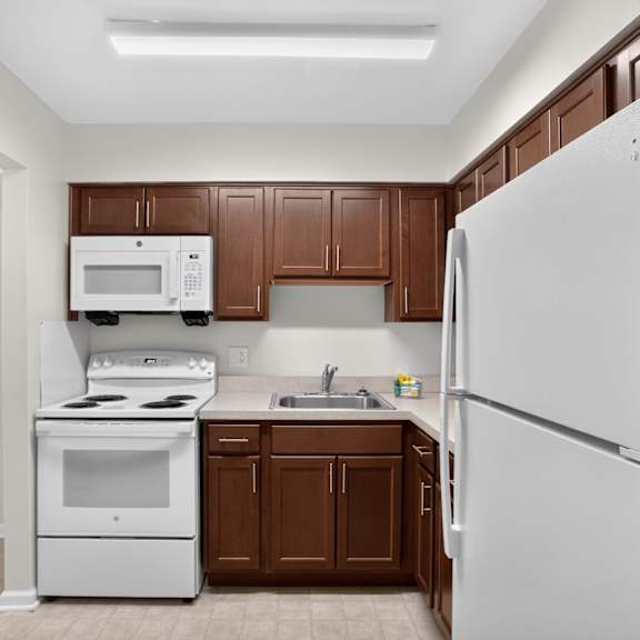 a white refrigerator stands in a kitchen with brown cabinets.