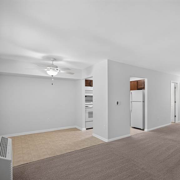a spacious room with a carpeted floor and a white ceiling fan.