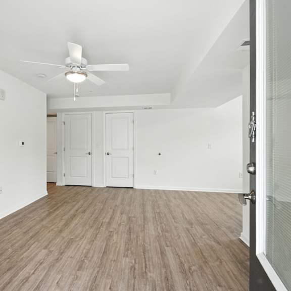 a room with a ceiling fan and wooden flooring.