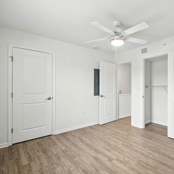 a room with a ceiling fan and wooden flooring.