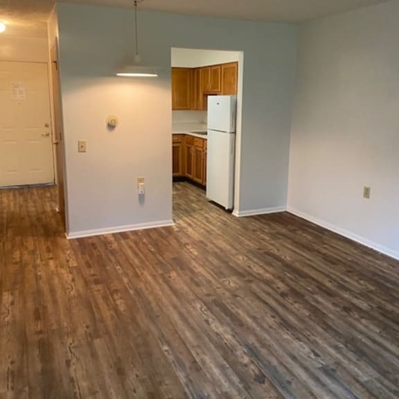 a room with wooden flooring and a white refrigerator.