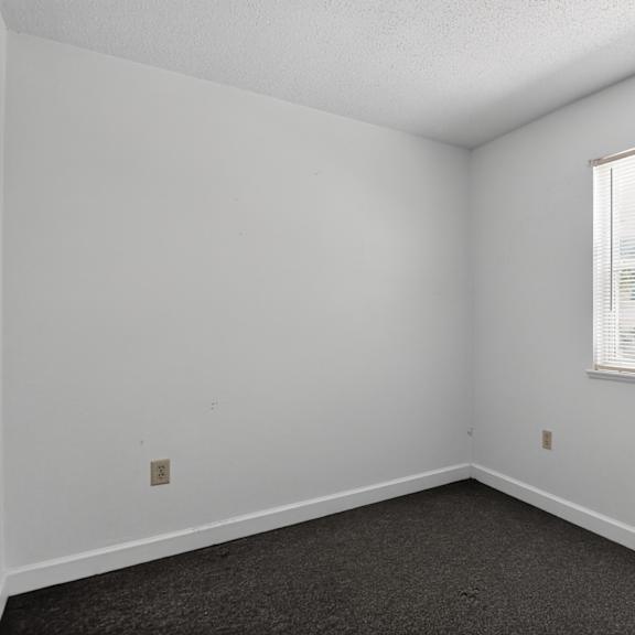 a room with a window and a carpeted floor.