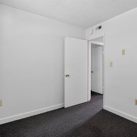 a white door is open in a room with carpeted floor.