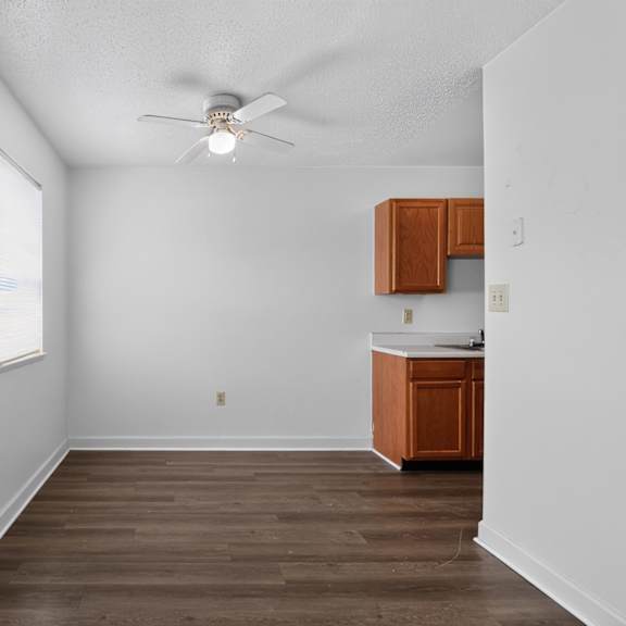 a room with a ceiling fan and wooden flooring.