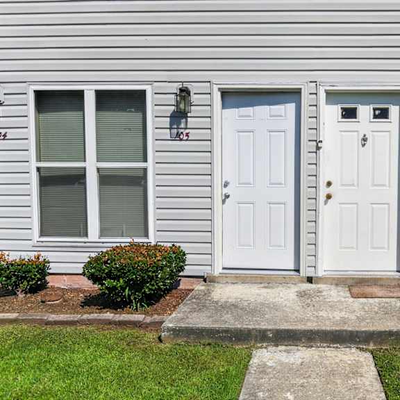a grey house with a white door and windows.