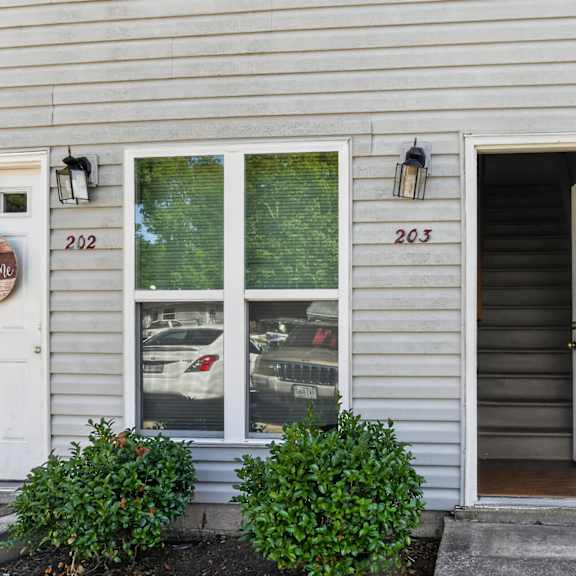 a house numbered 203 has a white door and a window with a red frame.