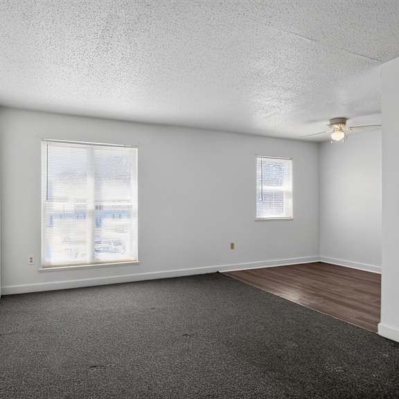 a sparsely furnished room with two windows.