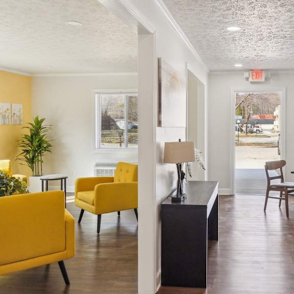 a yellow chair is in a room with tables and other chairs.