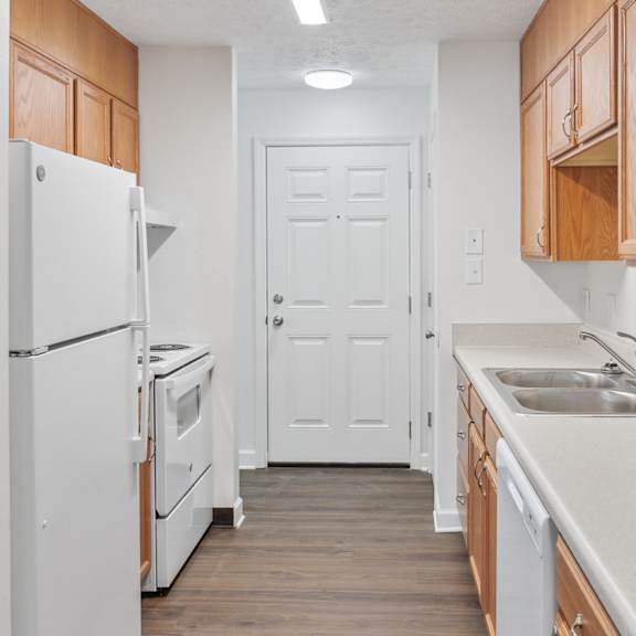 a kitchen with white appliances and wooden cabinets.