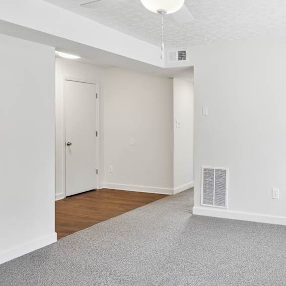 a room with a carpeted floor and a white ceiling fan.