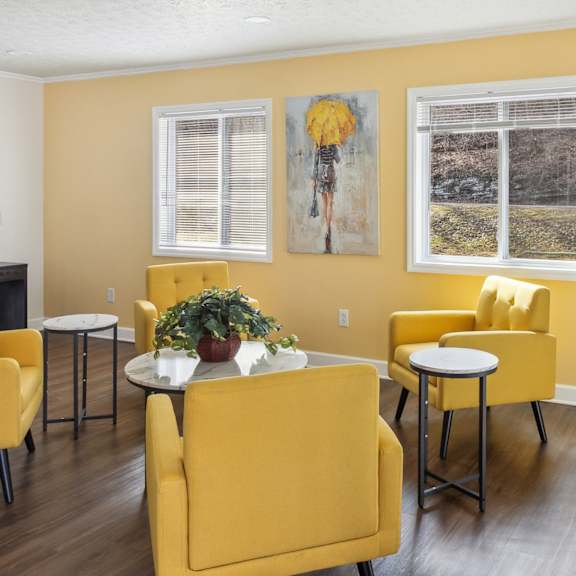a living room with yellow chairs and a white table.