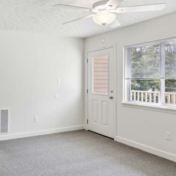 a room with a ceiling fan and a window with blinds.
