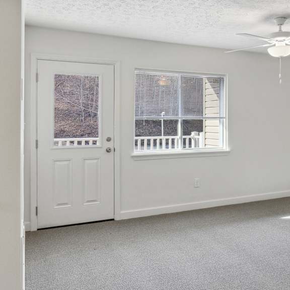 a room with a ceiling fan and a window with blinds.