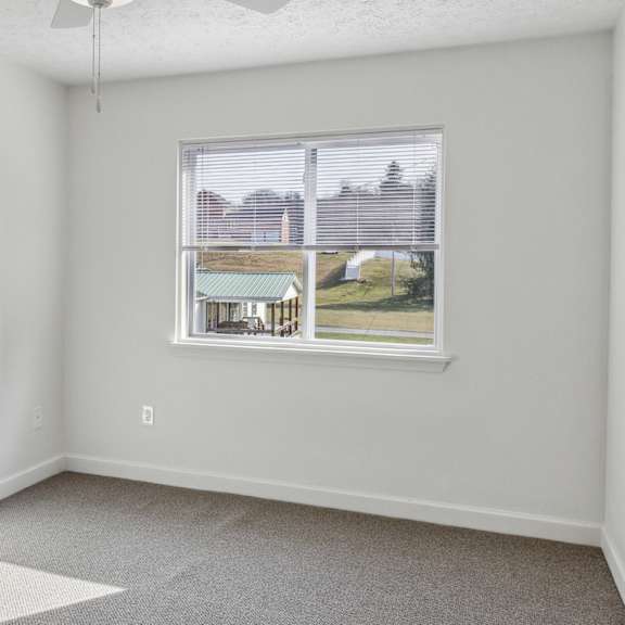 a room with a window showing a view of a house and trees.