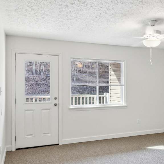 a room with a white door and a window with a view of a deck.