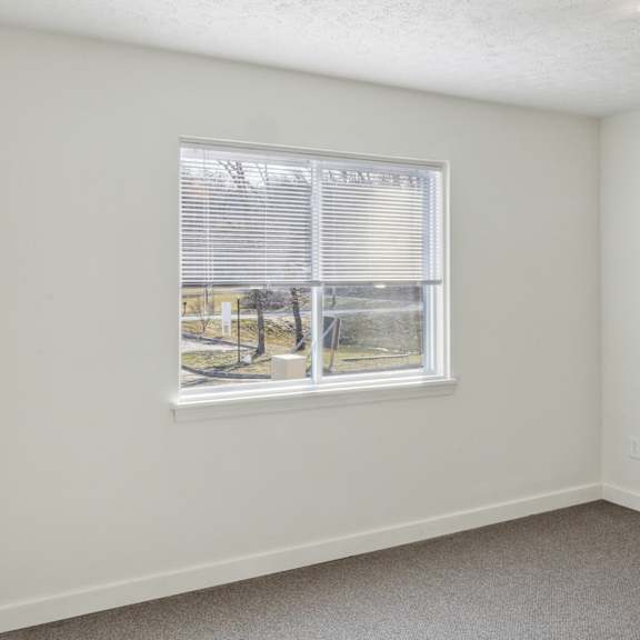a room with a window and a view of trees and a building outside.