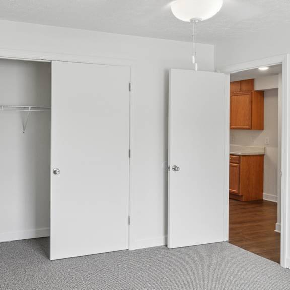 a white closet with a hanger bar and a white door.