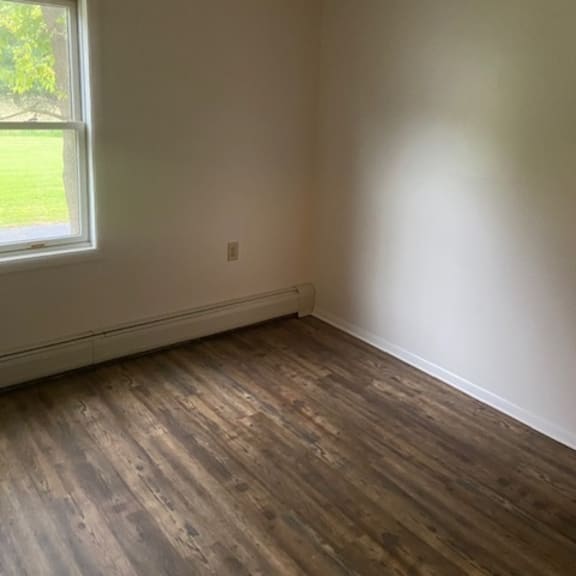 a room with a window and wooden flooring.