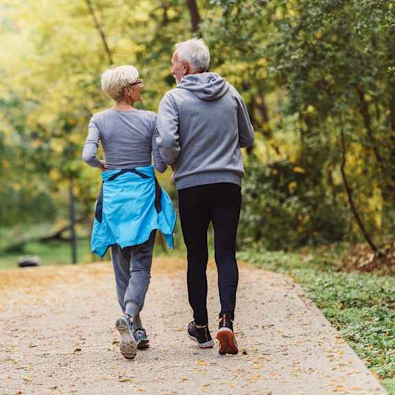 an older couple walking down a path in the park