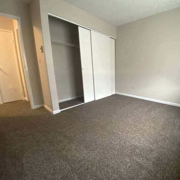 a bedroom with gray carpet and a closet