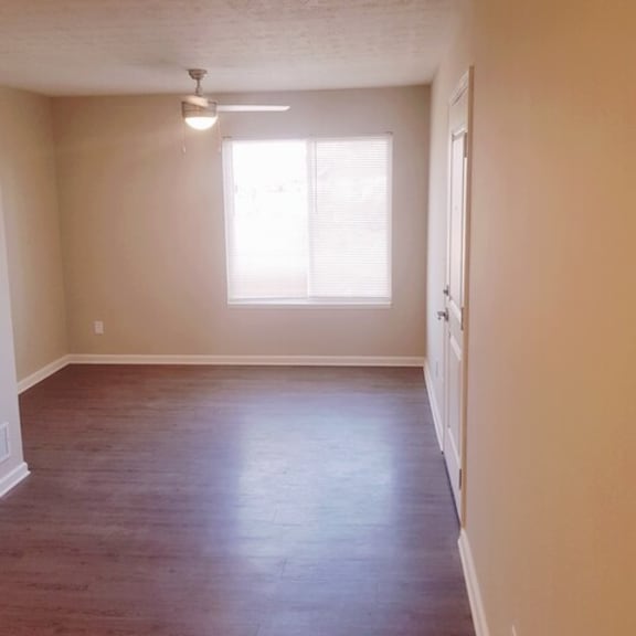 an empty living room with wood floors and a window