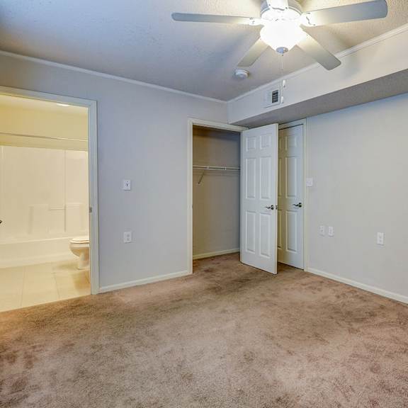 an empty living room with a ceiling fan and a closet