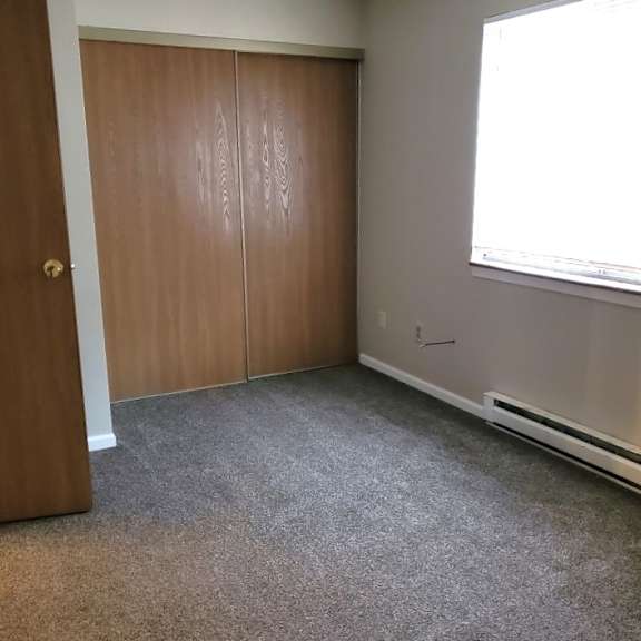 a bedroom with a carpeted floor and a closet