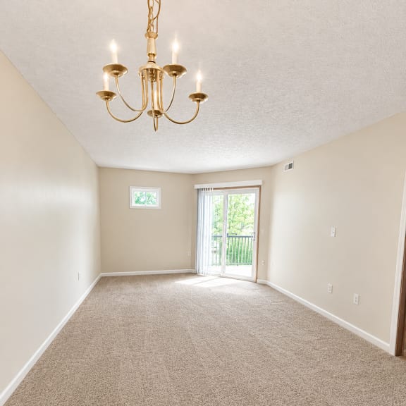 a room with a carpet floor and a chandelier hanging from the ceiling.