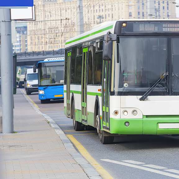 a green and white bus is driving down a street.