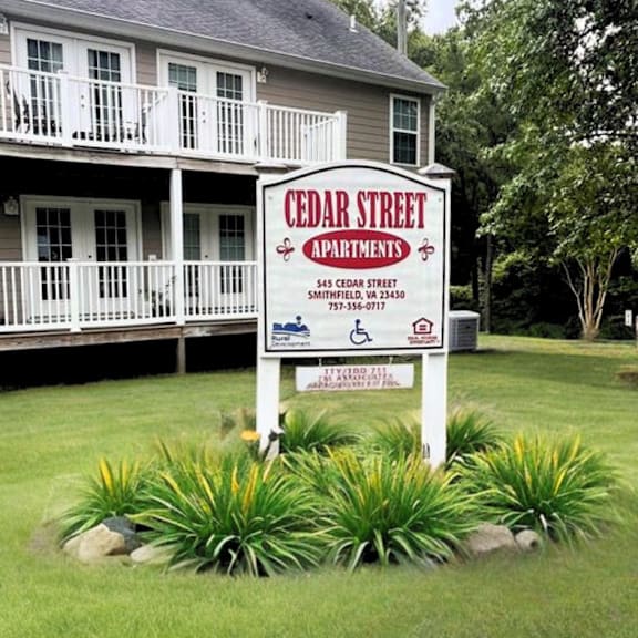 a sign in the front yard of a house with a white house