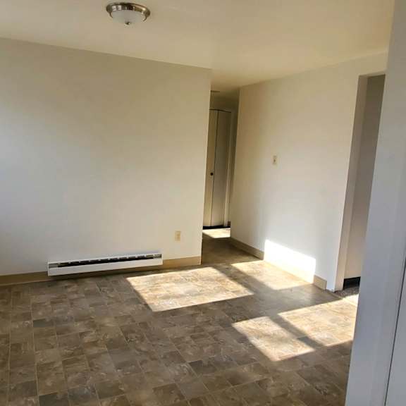 an empty living room with white walls and a window