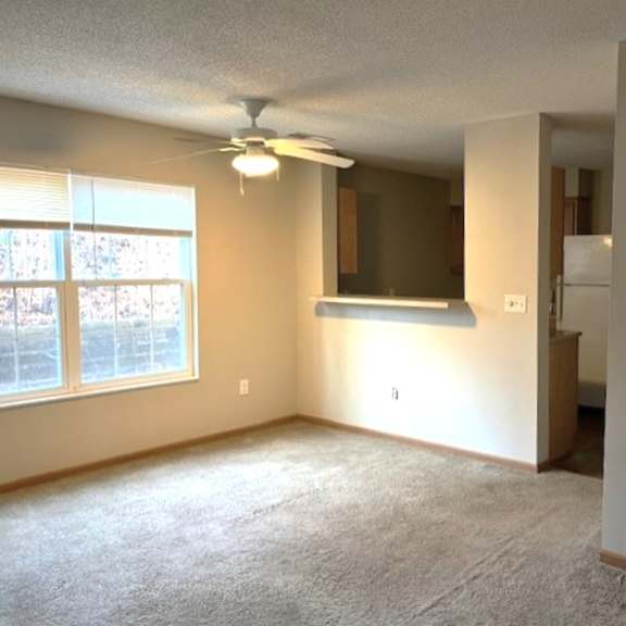 an empty living room with a ceiling fan and a window